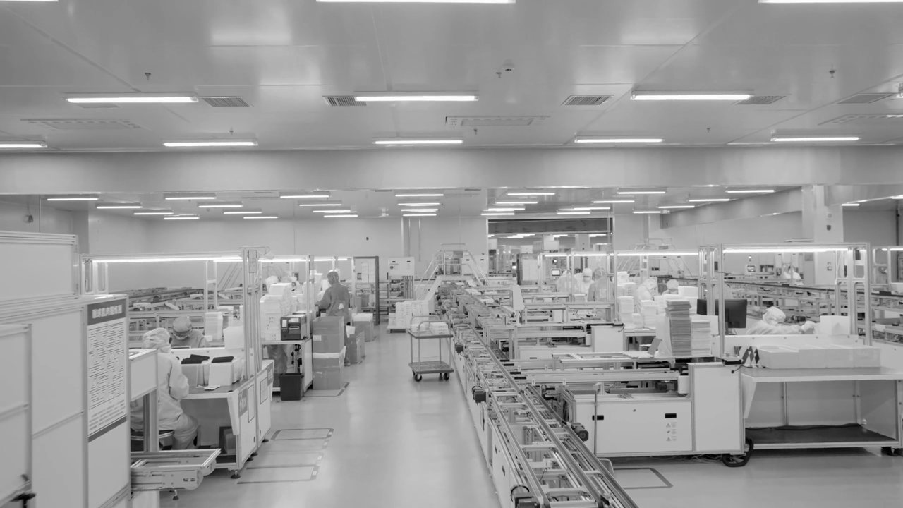Silent looping clip of a cleanroom production floor with process equipment and gowned operators.