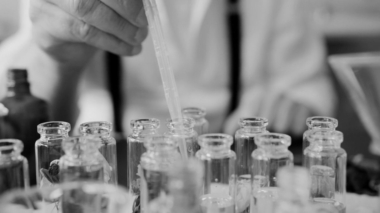 A pipette dosing small glass vials on a formulation bench