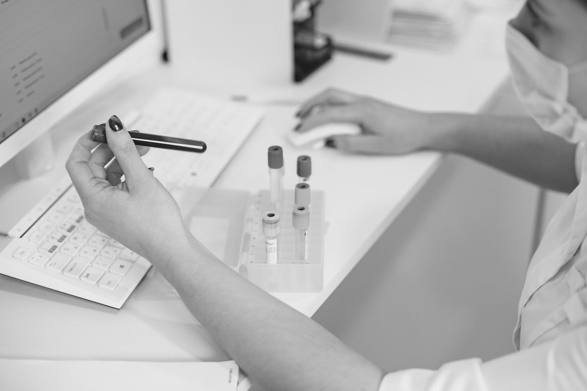 A technician logging results beside labelled sample tubes